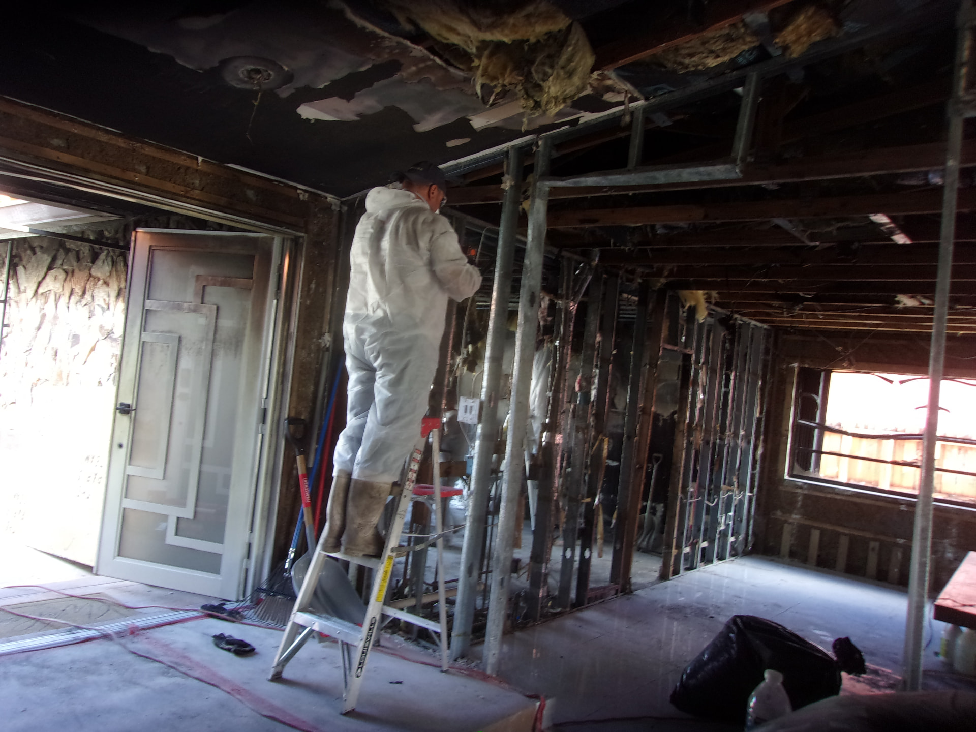 Technician in protective equipment working inside a soot-damaged property