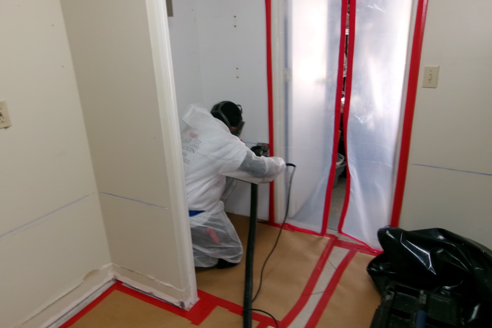 Technician in full protective gear performing contained mold remediation