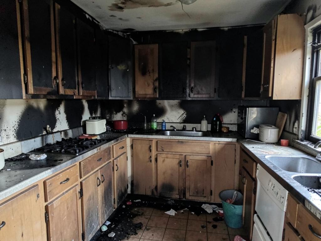 Kitchen with charred cabinets and heavy soot after a fire