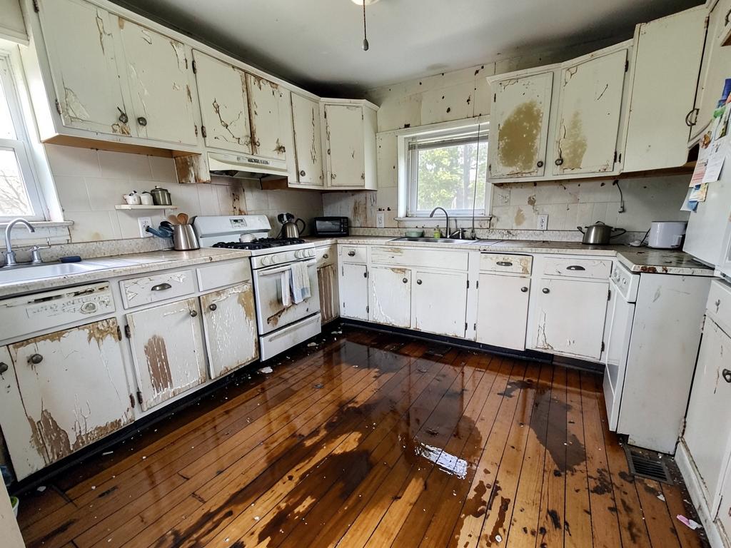 Kitchen with swollen cabinets and warped wet wood flooring