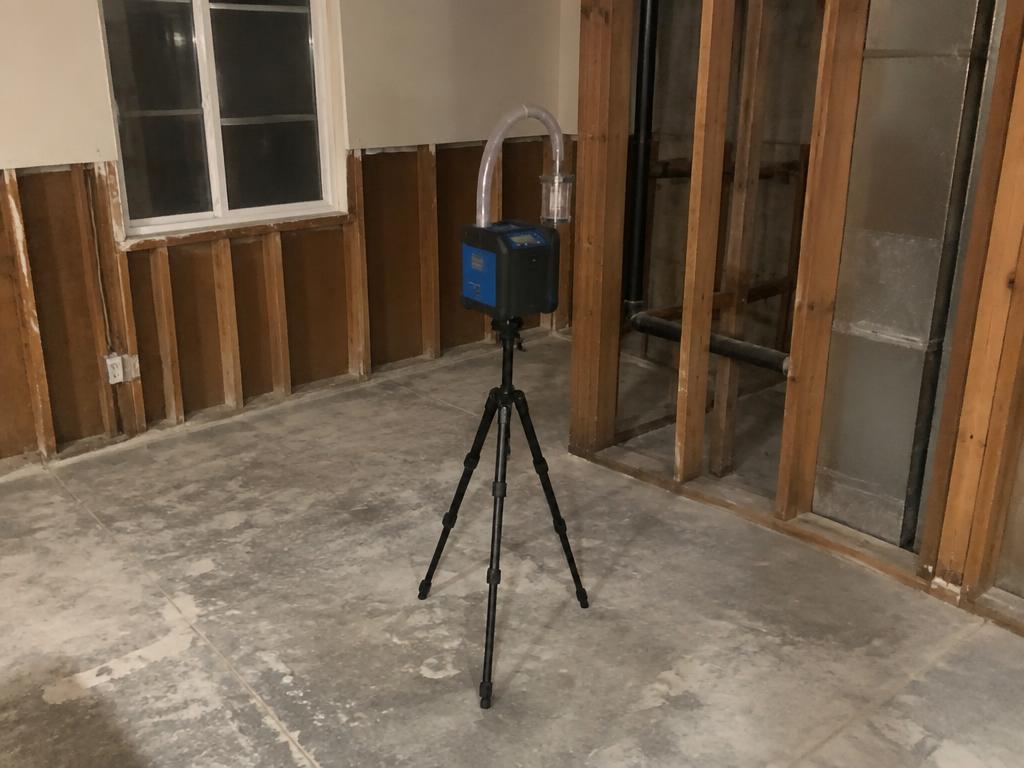 Air sampling pump set up in a stripped room for post-remediation testing
